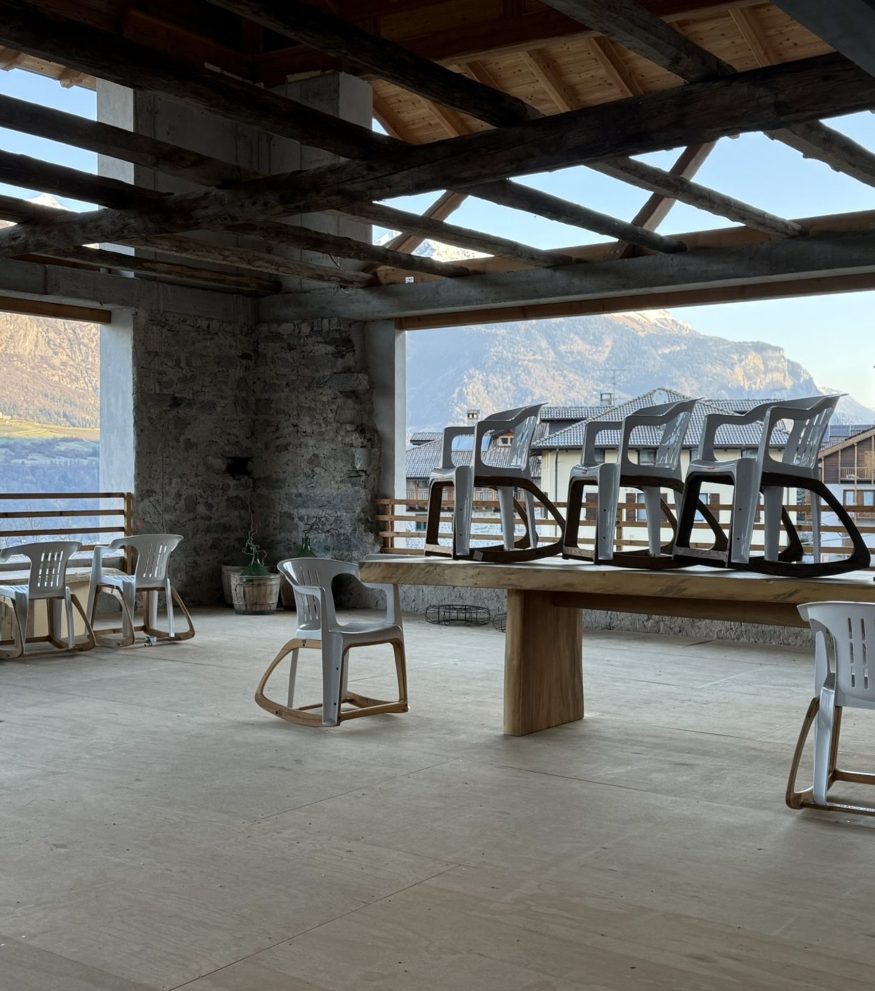 The Trento workshop: a timber-roofed loft with rocking chairs on a long oak table and the Dolomites behind
