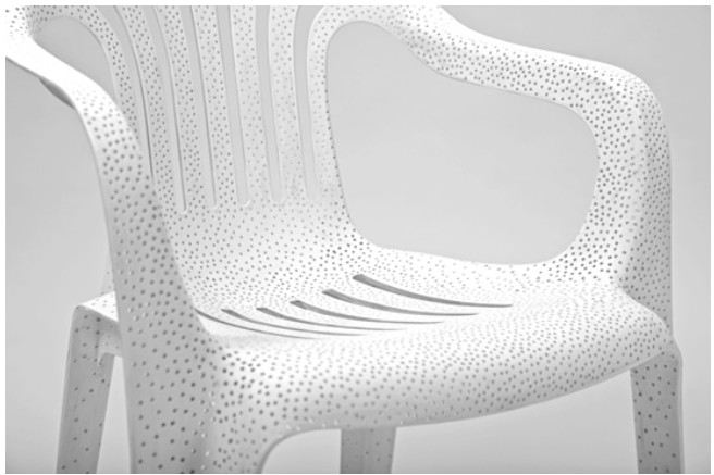 A white monobloc armchair from Tina Roeder's White Billion Chairs, its whole surface pierced with thousands of small holes