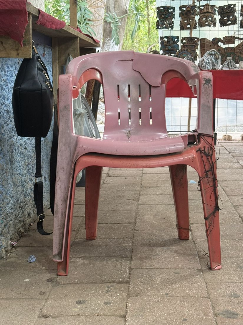 A pink armchair stacked on a red one, its cracked leg tied up with string