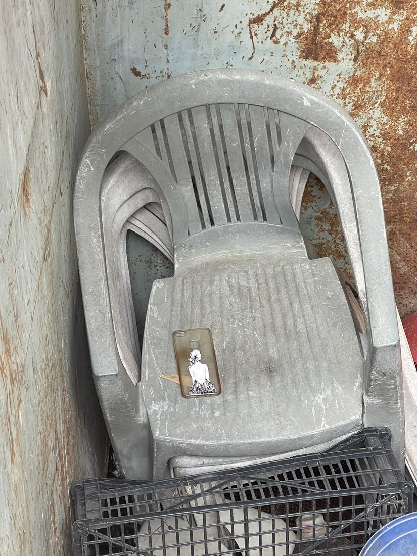 Grey stacked armchairs in a rusty corner, a phone case left on the seat