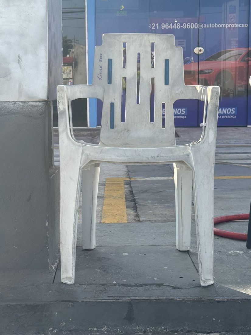 A white Linea 2000 armchair with blue inserts on a petrol-station forecourt